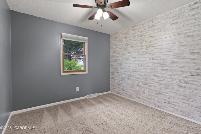empty room featuring visible vents, baseboards, ceiling fan, a textured ceiling, and carpet flooring