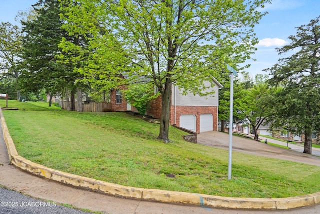 view of side of property featuring a yard, brick siding, fence, concrete driveway, and an attached garage
