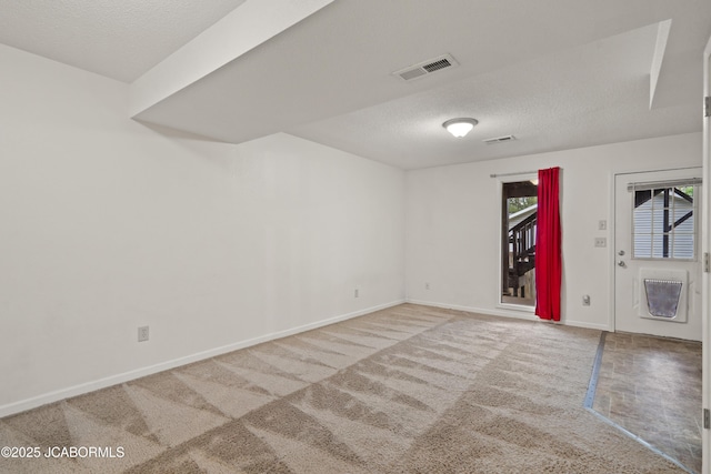 empty room with a textured ceiling, visible vents, baseboards, and carpet