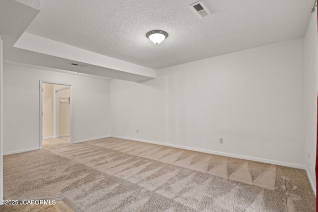 carpeted spare room with baseboards, a textured ceiling, and visible vents