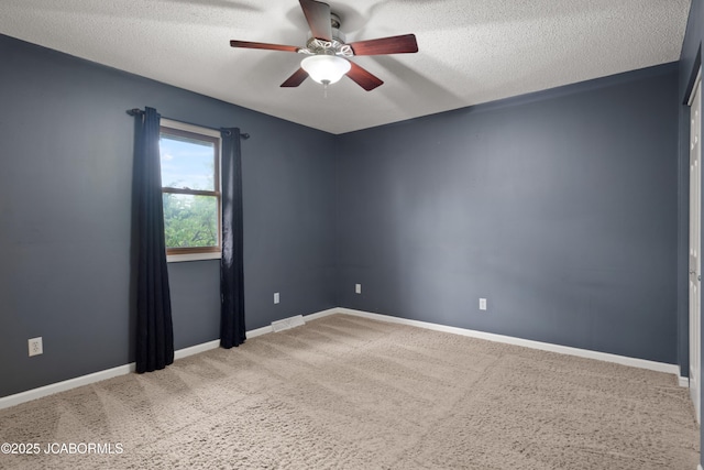 spare room with visible vents, carpet flooring, baseboards, a textured ceiling, and a ceiling fan