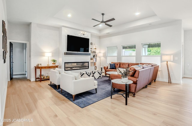 5621 Lightpost Dr, Columbia, MO 65201 - living room with a raised ceiling, light wood-type flooring, a glass covered fireplace, a ceiling fan, and recessed lighting