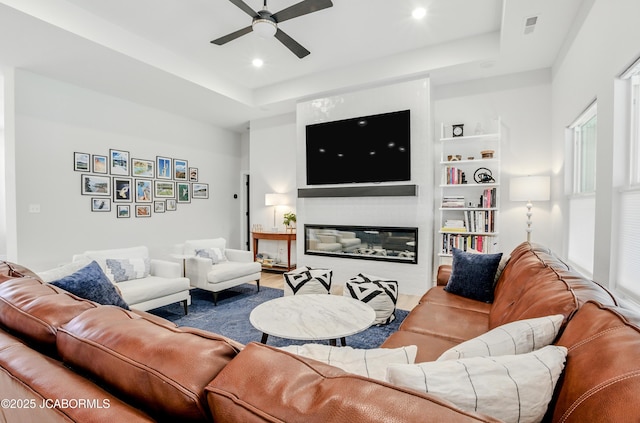 5621 Lightpost Dr, Columbia, MO 65201 - living room with ceiling fan, a tray ceiling, a glass covered fireplace, recessed lighting, and wood finished floors