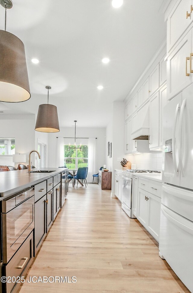 5621 Lightpost Dr, Columbia, MO 65201 - kitchen with white appliances, recessed lighting, custom range hood, light wood finished floors, and white cabinets