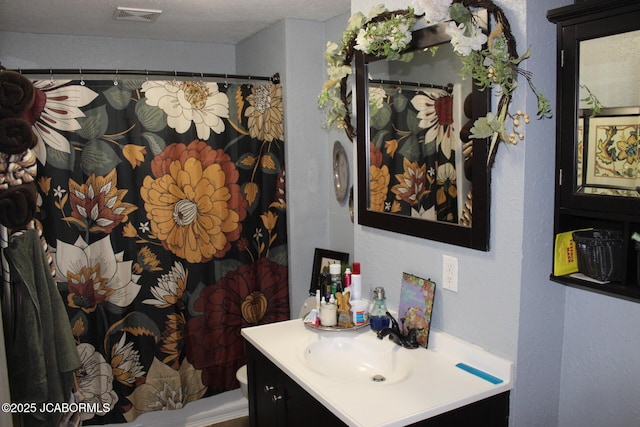 bathroom featuring visible vents, a textured ceiling, vanity, and toilet