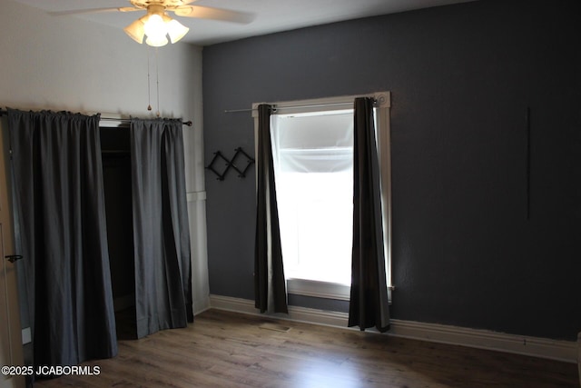 empty room with ceiling fan, baseboards, and wood finished floors