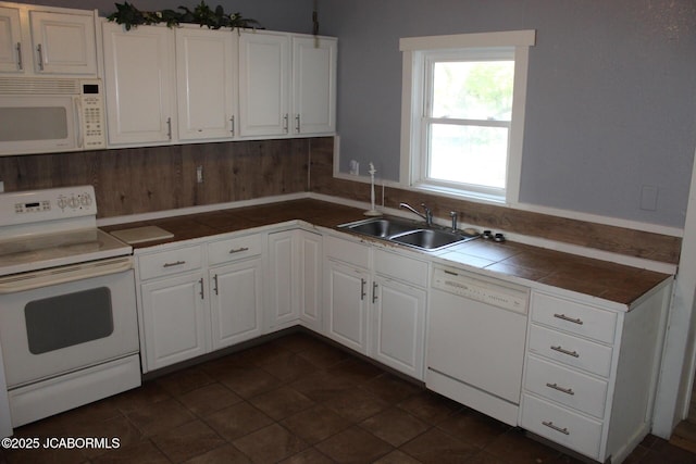 kitchen with tile countertops, white appliances, white cabinets, and a sink