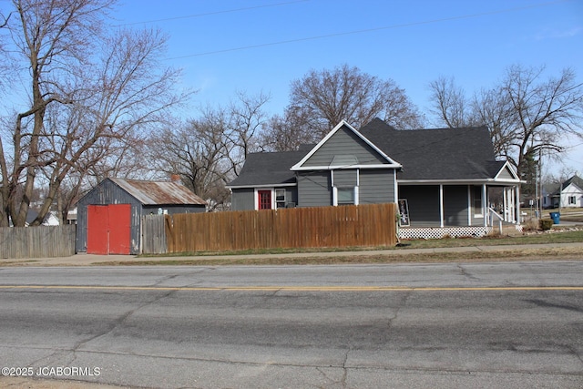 view of front of house with an outbuilding, fence, and a sunroom