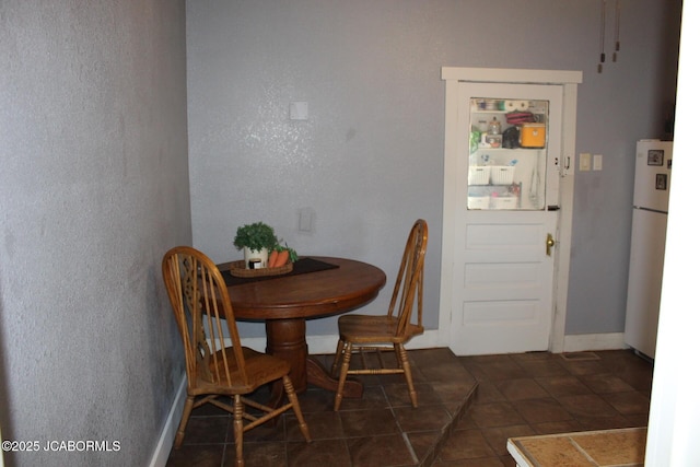 dining room with baseboards, a textured wall, and dark tile patterned flooring