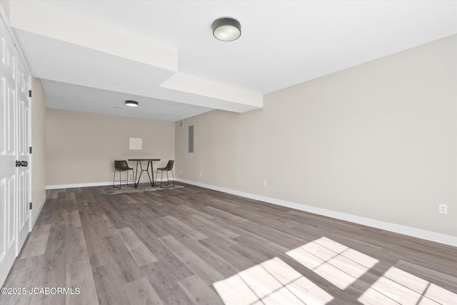 spare room featuring wood finished floors, electric panel, and baseboards