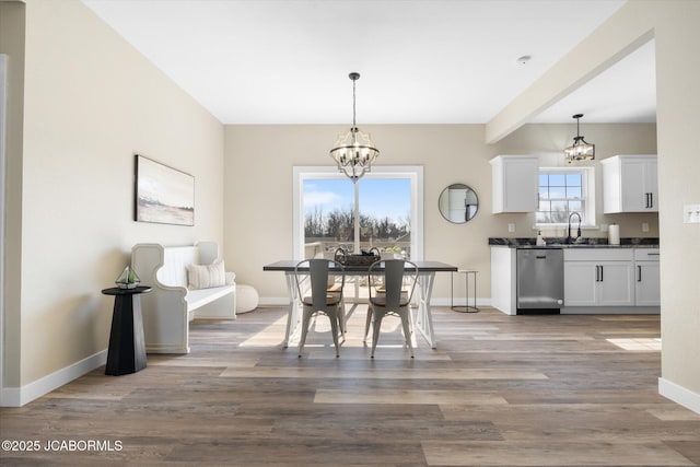 dining space with baseboards, light wood-style flooring, and a notable chandelier