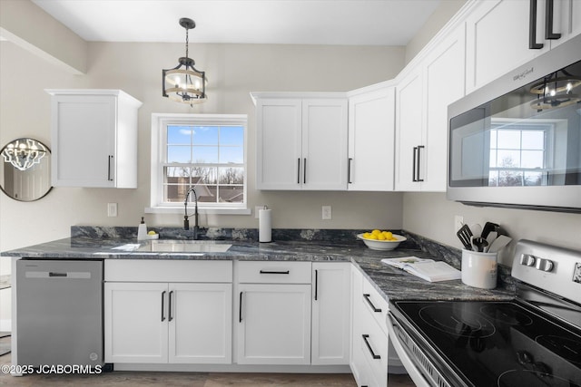 kitchen featuring appliances with stainless steel finishes, a sink, white cabinetry, and an inviting chandelier