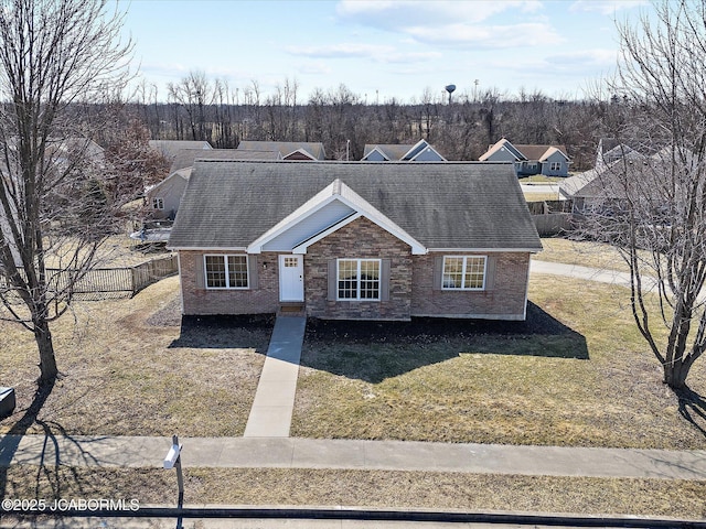 view of front of house featuring brick siding, a shingled roof, fence, and a front yard