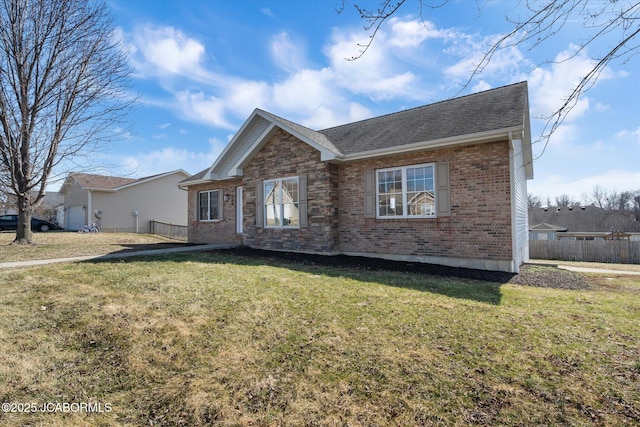 view of front of home with a shingled roof, brick siding, fence, and a front lawn