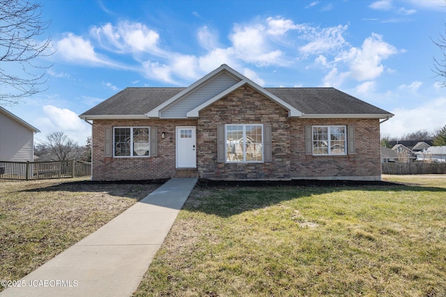 view of front of property featuring a shingled roof, fence, a front lawn, and brick siding