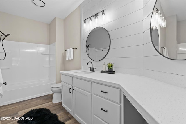 bathroom with vanity, tub / shower combination, wood finished floors, and toilet