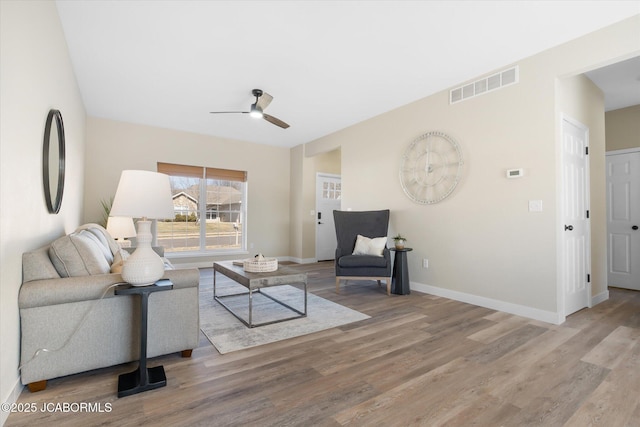 living area featuring a ceiling fan, baseboards, visible vents, and wood finished floors