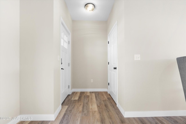 hallway featuring baseboards and wood finished floors