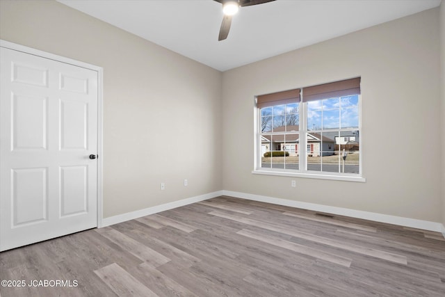 empty room with ceiling fan, wood finished floors, visible vents, and baseboards