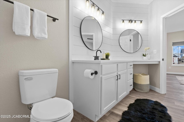 bathroom featuring vanity, wood finished floors, toilet, and baseboards