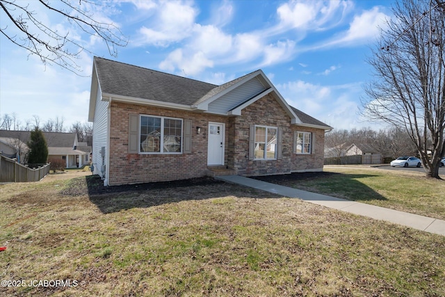 view of front of property with brick siding, a shingled roof, fence, and a front yard