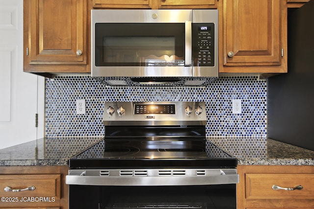 kitchen with appliances with stainless steel finishes, dark stone counters, and backsplash