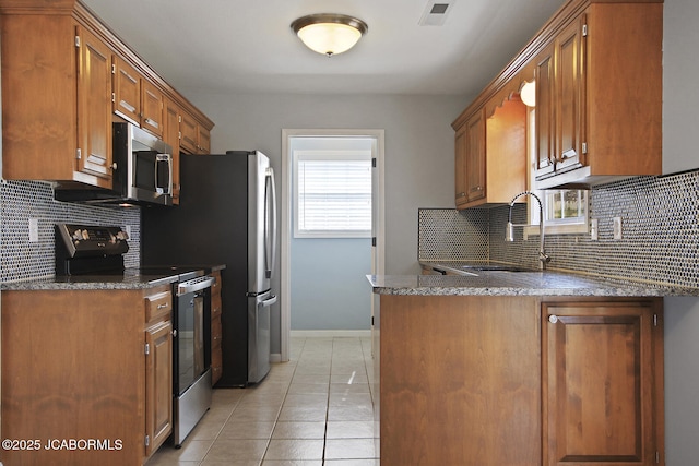 kitchen with appliances with stainless steel finishes, sink, decorative backsplash, and light tile patterned floors