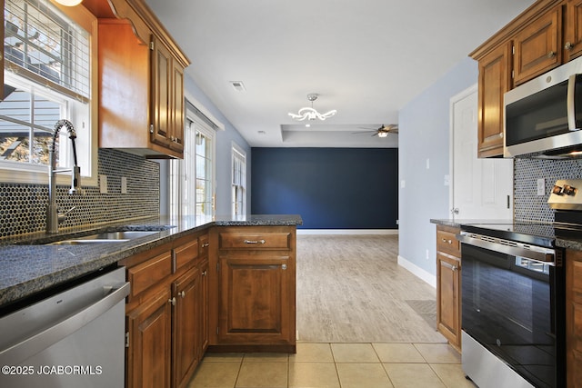 kitchen with a healthy amount of sunlight, appliances with stainless steel finishes, sink, and light tile patterned floors