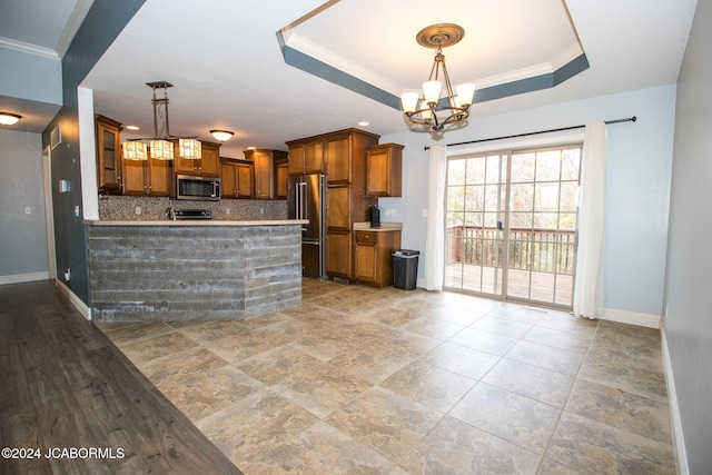 kitchen with decorative light fixtures, backsplash, appliances with stainless steel finishes, and a tray ceiling