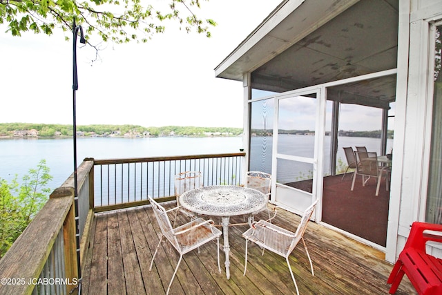 deck with a water view and outdoor dining space