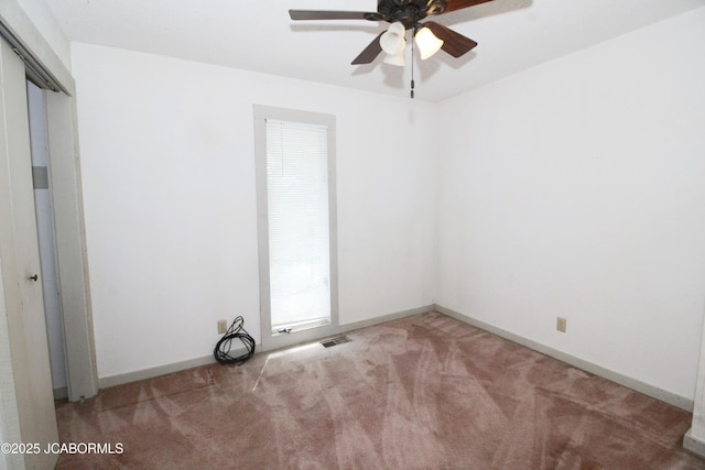 carpeted empty room featuring baseboards, ceiling fan, and visible vents