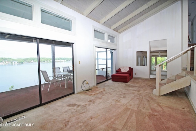 interior space featuring carpet floors, high vaulted ceiling, stairs, a water view, and visible vents