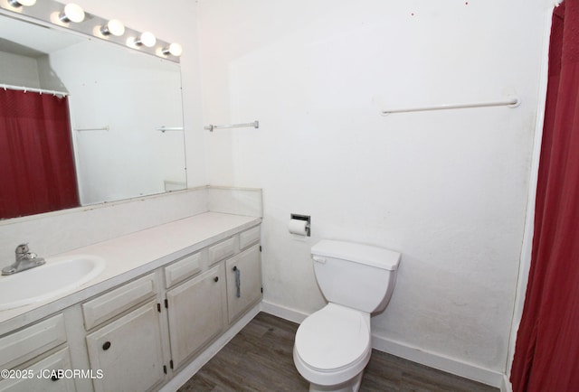 full bath with toilet, baseboards, wood finished floors, and vanity