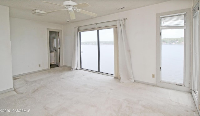 unfurnished room featuring a water view, a wealth of natural light, and carpet