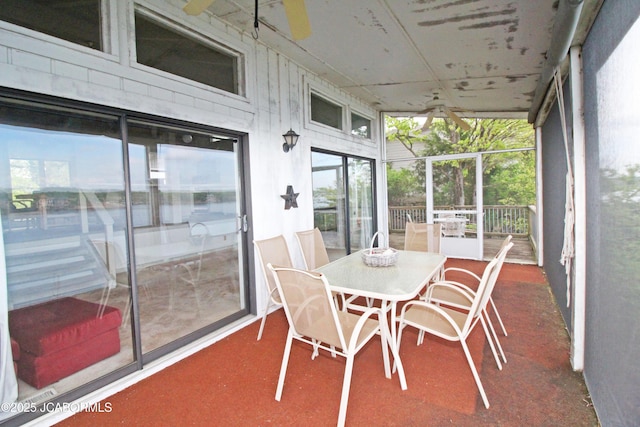sunroom with expansive windows, outdoor dining area, ceiling fan, and a wealth of natural light