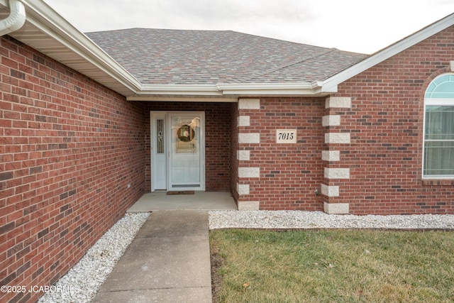 doorway to property with brick siding and a shingled roof