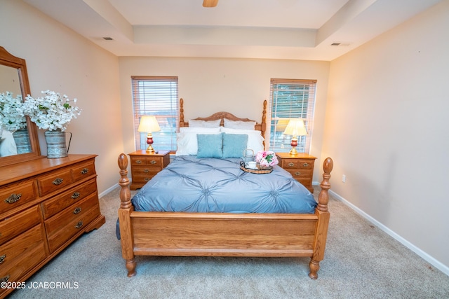 bedroom with a raised ceiling, multiple windows, carpet flooring, and visible vents