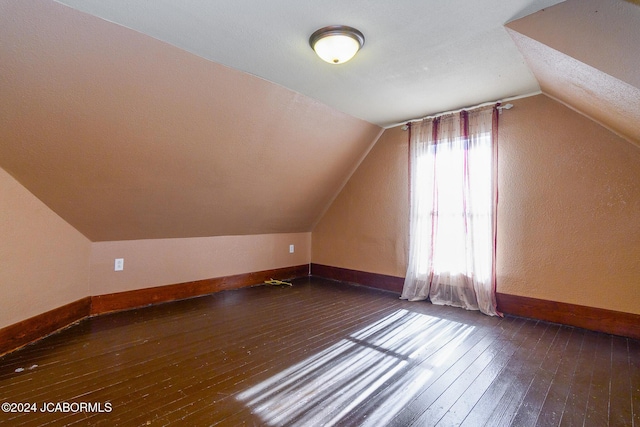 bonus room featuring dark wood-type flooring and vaulted ceiling