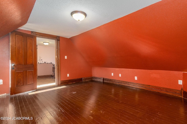 bonus room with vaulted ceiling, hardwood / wood-style floors, and a textured ceiling