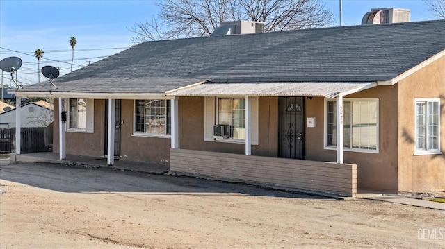 bungalow-style home with a porch, roof with shingles, and stucco siding