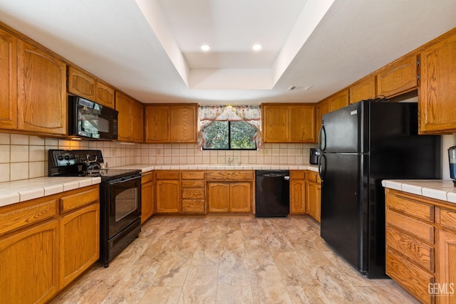 3113 Raccoon Dr, Lake Isabella, CA 93240 - kitchen featuring black appliances, brown cabinetry, a tray ceiling, backsplash, and a sink