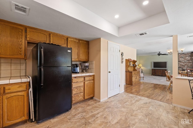 3113 Raccoon Dr, Lake Isabella, CA 93240 - kitchen with freestanding refrigerator, tile counters, a ceiling fan, brown cabinetry, and recessed lighting