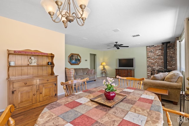 3113 Raccoon Dr, Lake Isabella, CA 93240 - dining area with a wood stove, ceiling fan, baseboards, and a chandelier