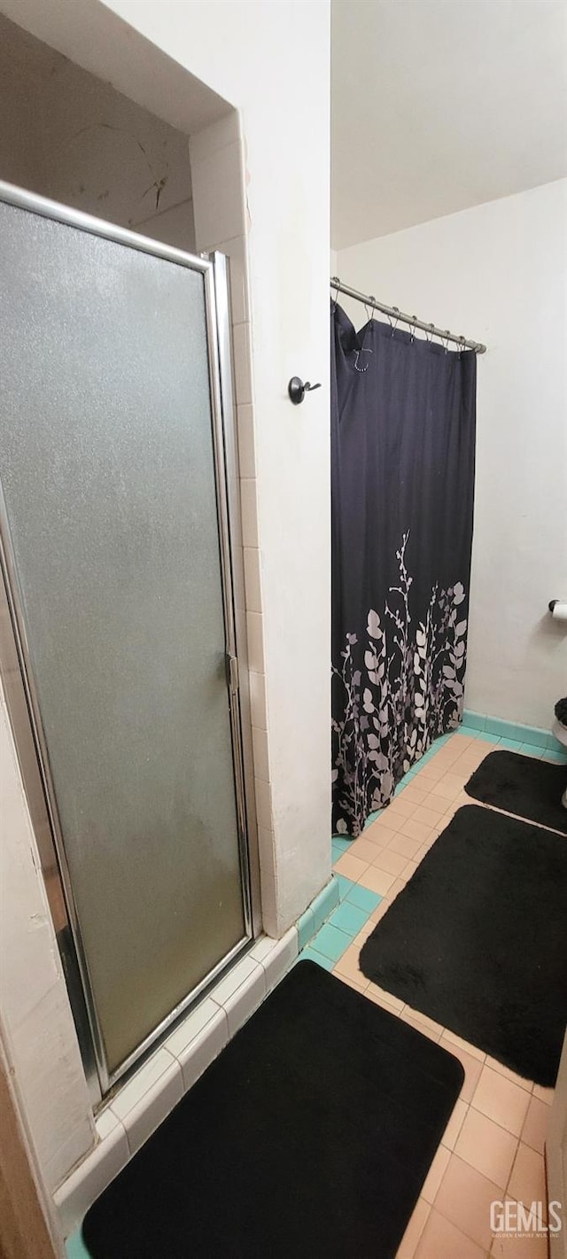 bathroom with tile patterned floors and a shower with door