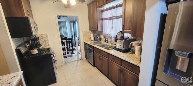 kitchen featuring light stone countertops, stainless steel fridge, sink, light tile patterned floors, and washer / clothes dryer