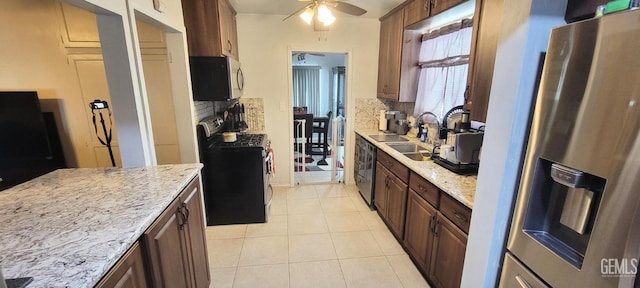 kitchen featuring ceiling fan, decorative backsplash, light stone countertops, appliances with stainless steel finishes, and light tile patterned flooring