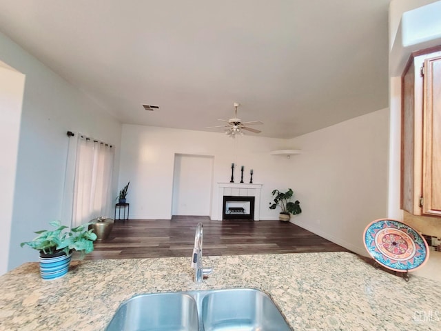 7205 Colony Park Dr, Bakersfield, CA 93313 - kitchen featuring a ceiling fan, wood finished floors, a tile fireplace, and light stone countertops
