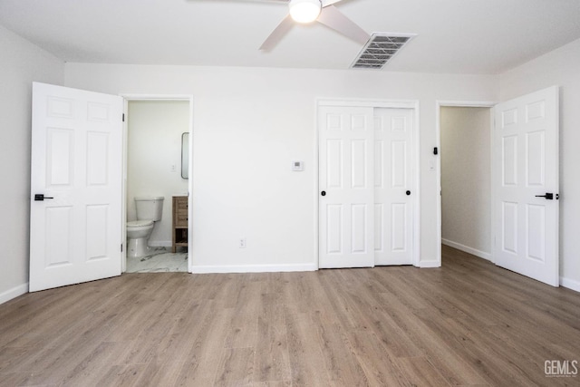 unfurnished bedroom featuring ceiling fan, light hardwood / wood-style flooring, ensuite bath, and a closet