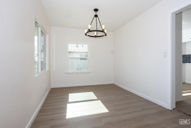 unfurnished room with hardwood / wood-style flooring and an inviting chandelier