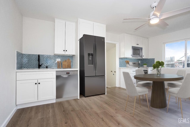 kitchen with sink, light hardwood / wood-style floors, white cabinets, and appliances with stainless steel finishes